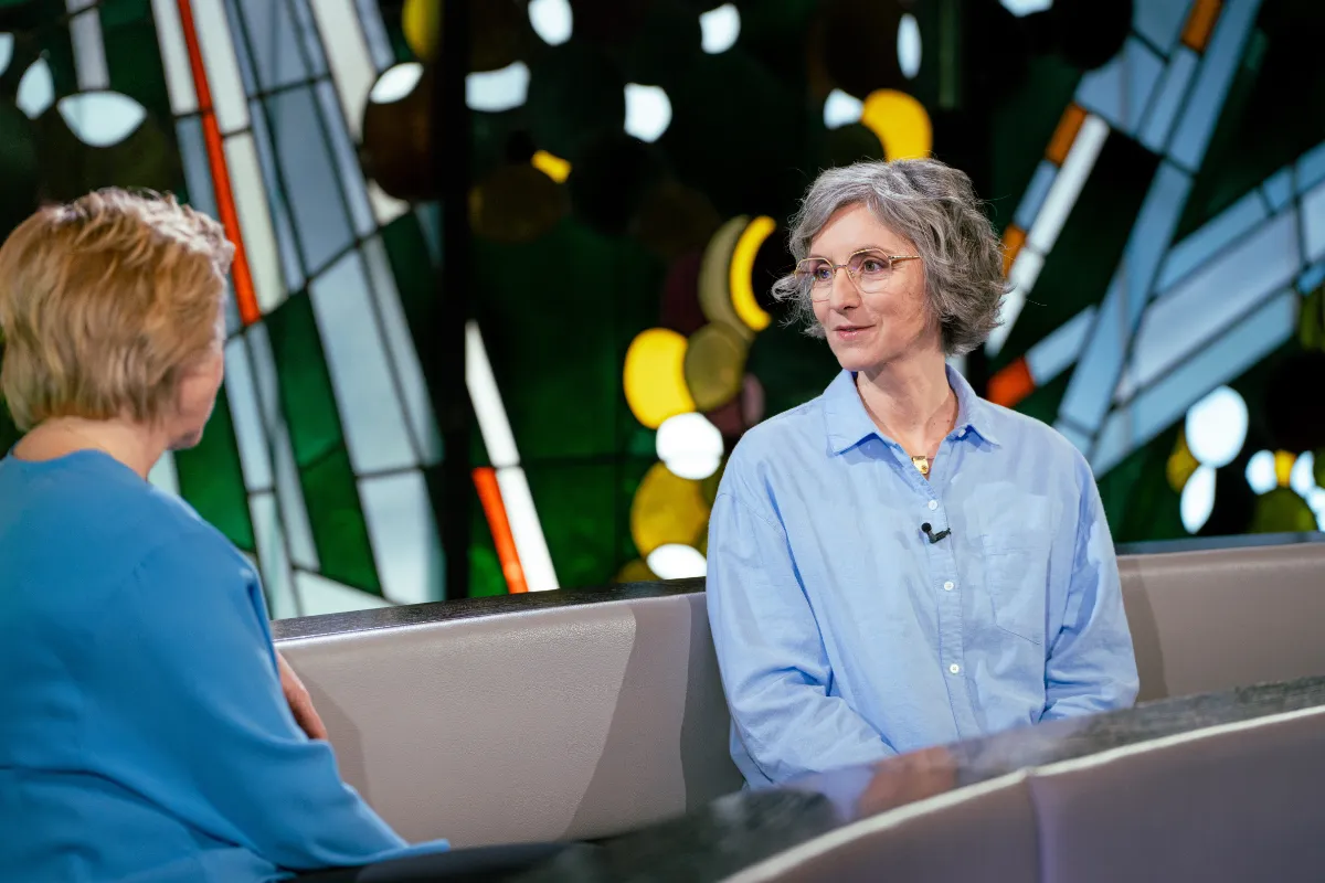 Manuela Hüttner sitzt vor einem bunten Kirchenfenster als Gast beim ZDF in der Sendung "die letzte Bank – Fragen an das Leben"